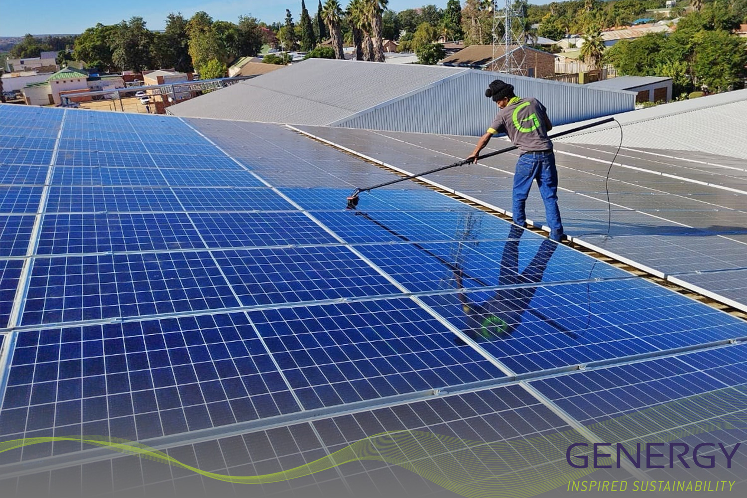 Man washing solar panels on rooftop with writing: GENERGY Inspired sustainability and green lines at bottom of image